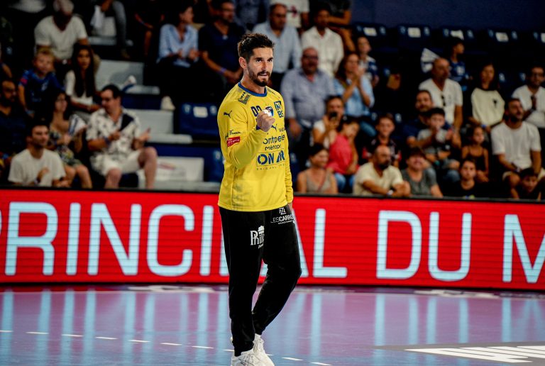Joueur de handball sur le terrain devant spectateurs.