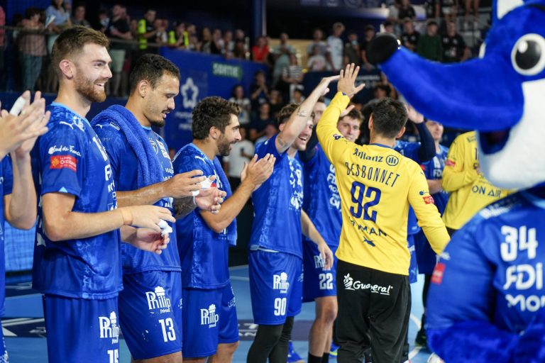 Joueurs de handball célébrant avec leur mascotte.