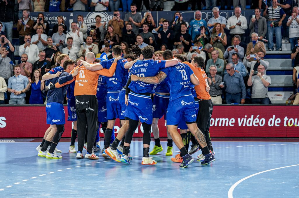 Équipe de handball célébrant victoire avec public enthousiaste.