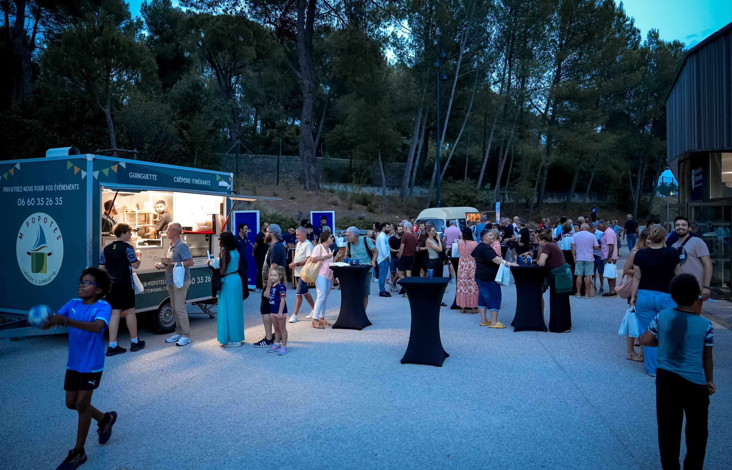 Foule autour d'un food truck en soirée.