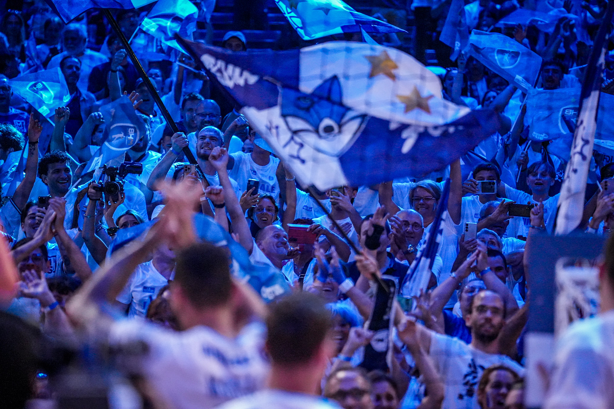 Foule en liesse avec drapeaux bleus.