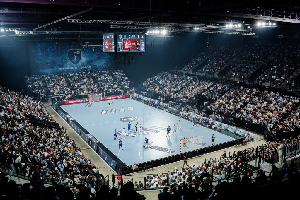 Match de handball dans une grande salle comble.